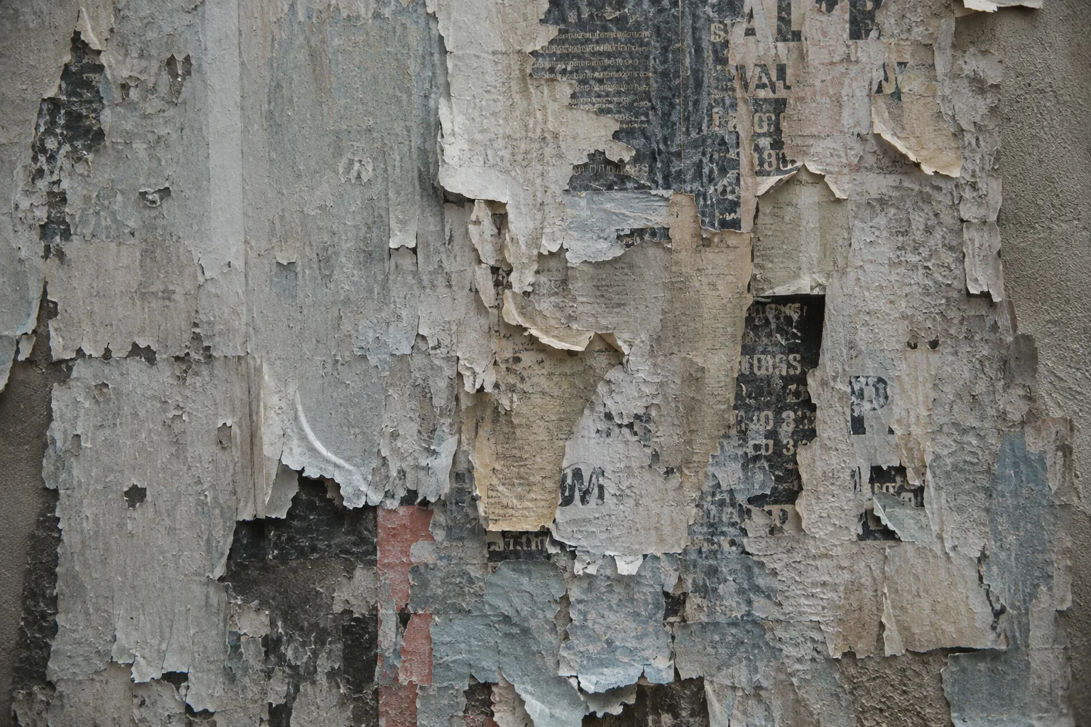 A wall where a poster has been pasted, torn and pasted again